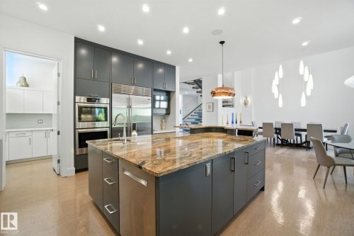 Kitchen featuring modern cabinets, appliances with stainless steel finishes, hanging light fixtures, light stone countertops, and recessed lighting - 11823 Saskatchewan Drive, Edmonton, AB - Indoor Photo Showing Kitchen With Upgraded Kitchen