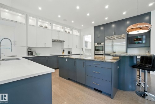 Kitchen with decorative light fixtures, a kitchen breakfast bar, a large island with sink, white cabinetry, and light wood finished floors - 11823 Saskatchewan Drive, Edmonton, AB - Indoor Photo Showing Kitchen With Upgraded Kitchen