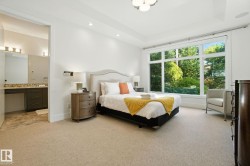 Bedroom featuring light carpet, a tray ceiling, recessed lighting, and connected bathroom - 
