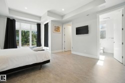 Bedroom with a tray ceiling, concrete flooring, connected bathroom, and recessed lighting - 