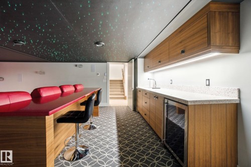 Indoor wet bar featuring dark stone countertops, beverage cooler, stairway, and modern cabinets - 11823 Saskatchewan Drive, Edmonton, AB -  Photo Showing Other Room