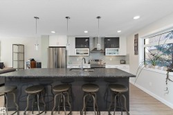 Kitchen featuring a kitchen breakfast bar, appliances with stainless steel finishes, a large island with sink, backsplash, and recessed lighting - 