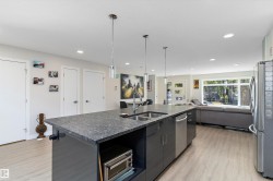 Kitchen featuring open floor plan, stainless steel appliances, an island with sink, hanging light fixtures, and light wood finished floors - 