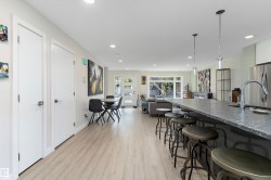 Kitchen with hanging light fixtures, light wood-type flooring, open floor plan, freestanding refrigerator, and a breakfast bar area - 
