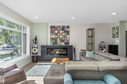 Living area with wood finished floors, recessed lighting, and a glass covered fireplace - 