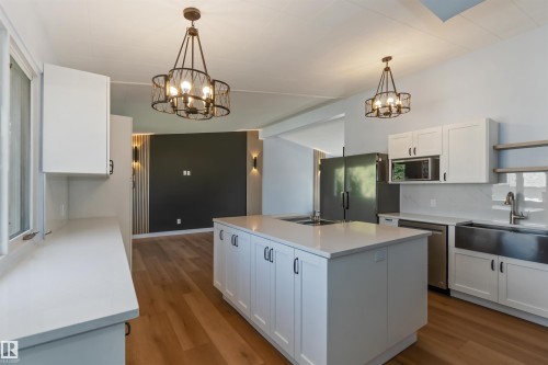 Kitchen with white cabinets, light wood-style flooring, a center island, and pendant lighting - 6808 95 Avenue, Edmonton, AB - Indoor Photo Showing Kitchen