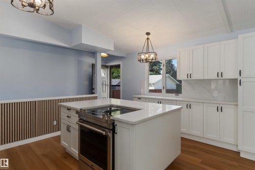 Kitchen featuring a chandelier, stainless steel electric stove, white cabinets, and wainscoting - 6808 95 Avenue, Edmonton, AB - Indoor Photo Showing Kitchen