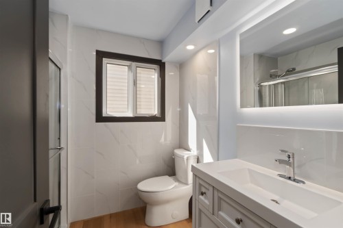 Full bathroom with vanity, a marble finish shower, tile walls, recessed lighting, and light wood-style floors - 6808 95 Avenue, Edmonton, AB - Indoor Photo Showing Bathroom