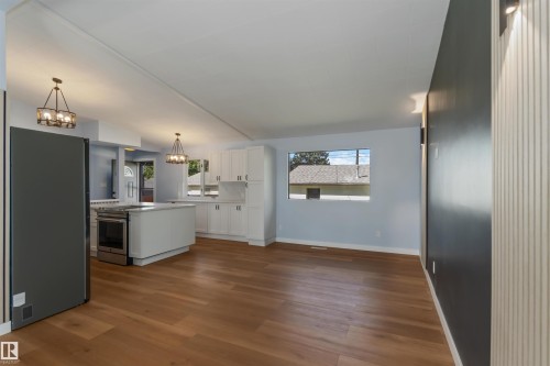 Kitchen featuring white cabinetry, appliances with stainless steel finishes, a kitchen island, light wood-type flooring, and pendant lighting - 6808 95 Avenue, Edmonton, AB - Indoor Photo Showing Kitchen