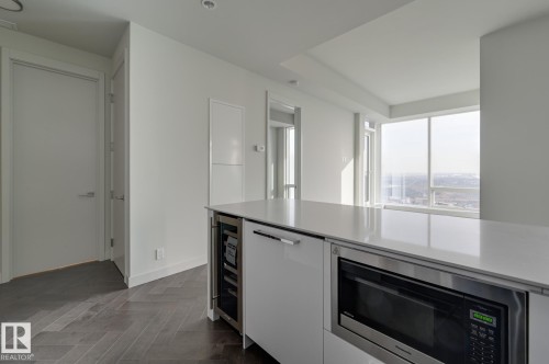 Kitchen featuring stainless steel microwave, wine cooler, and white cabinetry - 4503 10360 102 Nw, Edmonton, AB - Indoor Photo Showing Kitchen
