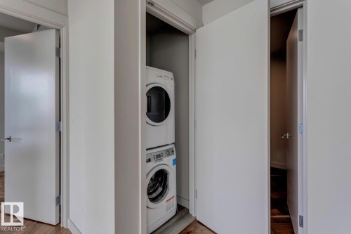 Washroom featuring stacked washer / drying machine and light wood finished floors - 4503 10360 102 Nw, Edmonton, AB - Indoor Photo Showing Laundry Room
