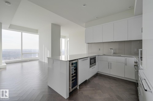 Kitchen with a peninsula, white cabinetry, modern cabinets, beverage cooler, and open floor plan - 4503 10360 102 Nw, Edmonton, AB - Indoor Photo Showing Kitchen