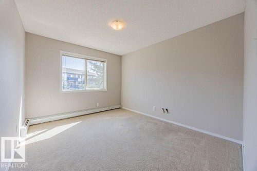 Spare room with a textured ceiling, carpet flooring, and a baseboard heating unit - Edmonton, AB - Indoor Photo Showing Other Room