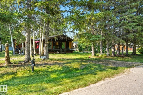 View of grassy yard with covered porch - 6309 49 St, Rural Wetaskiwin County, AB - Outdoor