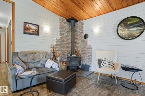 Living room featuring a wood stove, lofted ceiling, wooden walls, and wood ceiling - 6309 49 St, Rural Wetaskiwin County, AB -  With Fireplace