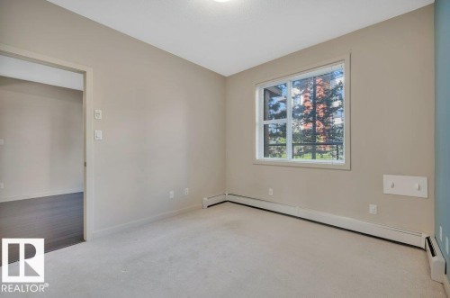 Carpeted spare room featuring baseboard heating, vaulted ceiling, and a baseboard heating unit - 140 308 Ambleside Link, Edmonton, AB - Indoor Photo Showing Other Room