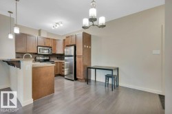 Kitchen with backsplash, pendant lighting, brown cabinetry, appliances with stainless steel finishes, and a breakfast bar area - 
