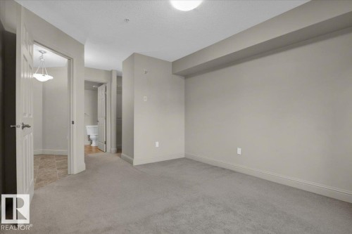 Spare room featuring light carpet and a textured ceiling - 226 13111 140 Avenue, Edmonton, AB - Indoor Photo Showing Other Room