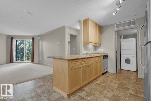 Kitchen featuring light brown cabinetry, a peninsula, open floor plan, light countertops, and freestanding refrigerator - 226 13111 140 Avenue, Edmonton, AB - Indoor