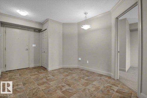 Entryway featuring crown molding, stone finish flooring, and a textured ceiling - 226 13111 140 Avenue, Edmonton, AB - Indoor Photo Showing Other Room
