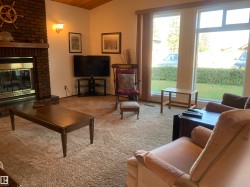 Carpeted living room with a brick fireplace, vaulted ceiling, and wooden ceiling - 