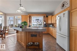 Kitchen featuring open shelves, freestanding refrigerator, hanging light fixtures, a center island, and a breakfast bar area - 