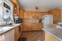 Kitchen featuring tasteful backsplash, vaulted ceiling, white appliances, open shelves, and light stone countertops - 
