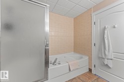 Bathroom featuring tile patterned floors, a bath, tile walls, a shower stall, and a drop ceiling - 