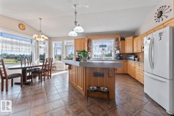 Kitchen with freestanding refrigerator, decorative light fixtures, open shelves, lofted ceiling, and a center island - 