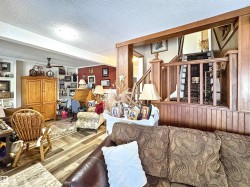 Living room with a textured ceiling, wood finished floors, stairs, and beamed ceiling - 