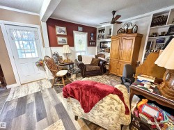 Living area with a textured ceiling, wood finished floors, wainscoting, crown molding, and a ceiling fan - 
