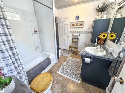 Bathroom with vanity, shower / bathtub combination with curtain, and tile walls - 