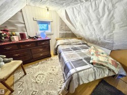 Bedroom featuring light wood-type flooring, lofted ceiling, and wood walls - 