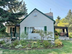View of home's exterior with a shingled roof, a wooden deck, and a lawn - 