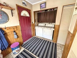 Laundry area with wooden walls, ornamental molding, a wainscoted wall, and washing machine and dryer - 