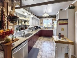 Kitchen featuring dishwasher, stone finish flooring, decorative backsplash, pendant lighting, and open shelves - 