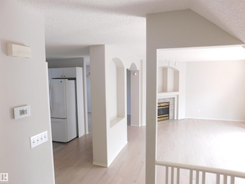 Hallway with light wood-style flooring, a textured ceiling, arched walkways, and vaulted ceiling - 26 1295 Carter Crest Road, Edmonton, AB - Indoor Photo Showing Other Room