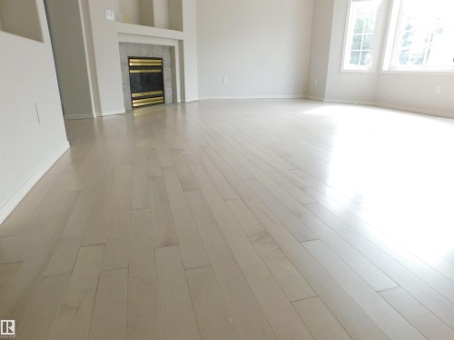 Unfurnished living room featuring a fireplace and light wood-style floors - 26 1295 Carter Crest Road, Edmonton, AB - Indoor With Fireplace