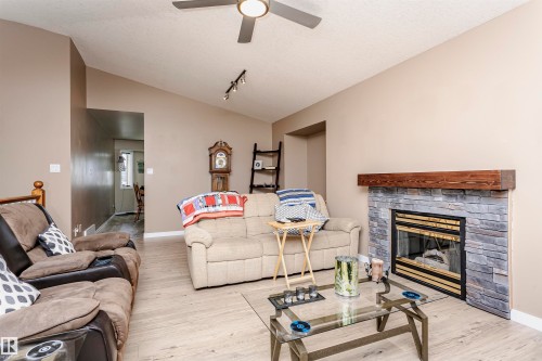 Living area with lofted ceiling, a textured ceiling, wood finished floors, a fireplace, and rail lighting - 8 Lafond Drive, Tofield, AB - Indoor Photo Showing Living Room With Fireplace