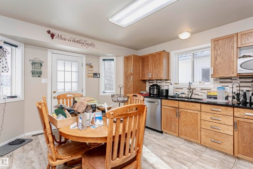Kitchen featuring backsplash, dark countertops, plenty of natural light, and stainless steel dishwasher - 8 Lafond Drive, Tofield, AB - Indoor