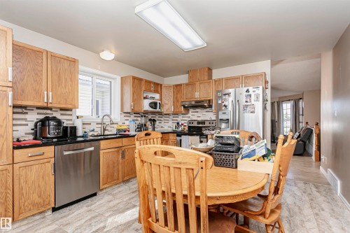 Kitchen with backsplash, dark countertops, plenty of natural light, and stainless steel appliances - 8 Lafond Drive, Tofield, AB - Indoor