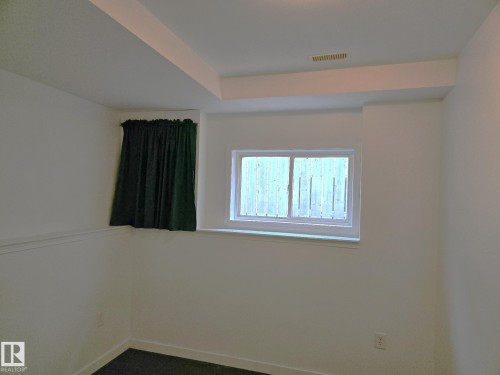 Empty room with dark colored carpet and a raised ceiling - 8 Lafond Drive, Tofield, AB - Indoor