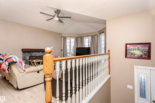 Living room featuring a textured ceiling, light wood-style flooring, a fireplace, and ceiling fan - 8 Lafond Drive, Tofield, AB - Indoor Photo Showing Other Room