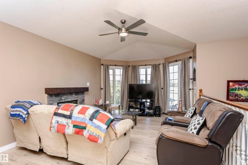 Living area with a textured ceiling, healthy amount of natural light, light wood-style flooring, a fireplace, and ceiling fan - 8 Lafond Drive, Tofield, AB - Indoor Photo Showing Living Room With Fireplace