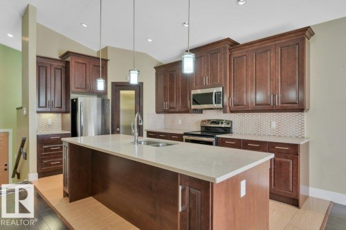 Kitchen with stainless steel appliances, pendant lighting, backsplash, light stone counters, and a kitchen island with sink - 6221 167A Avenue, Edmonton, AB - Indoor Photo Showing Kitchen With Double Sink With Upgraded Kitchen