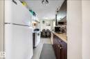 Kitchen with white appliances, dark brown cabinetry, a textured ceiling, light wood-type flooring, and backsplash - 285 Harrison Drive, Edmonton, AB  - Indoor Photo Showing Kitchen With Double Sink 