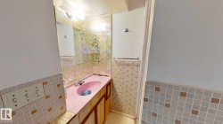 Half bathroom featuring tile walls, light tile patterned floors, vanity, and a wainscoted wall - 