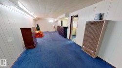 Corridor featuring wood walls, a heating unit, and carpet - 