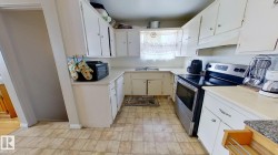 Kitchen with stainless steel range with electric cooktop, white cabinetry, under cabinet range hood, and light countertops - 