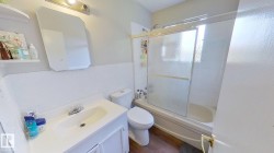 Full bath with bath / shower combo with glass door, vanity, dark wood-type flooring, and a wainscoted wall - 